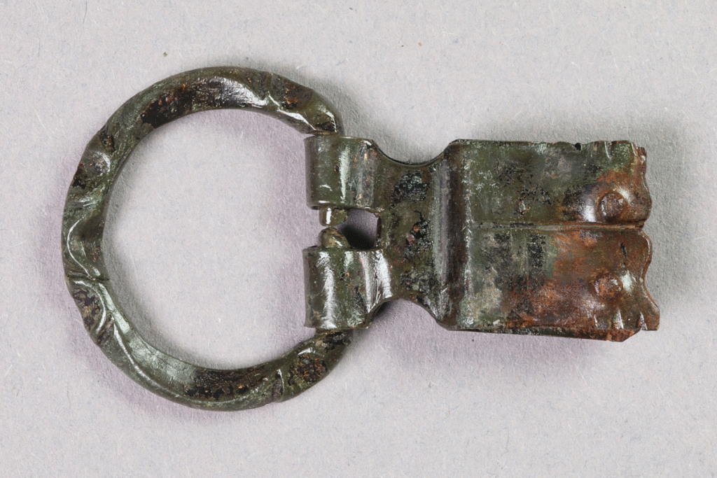 Schnalle aus Buntmetall von der Burg Bartenstein, Anfang 14. Jh., Partenstein, Museum Ahler Kram, Fd. Nr. 1215, H. 2,8 cm, Br. 4,8 cm